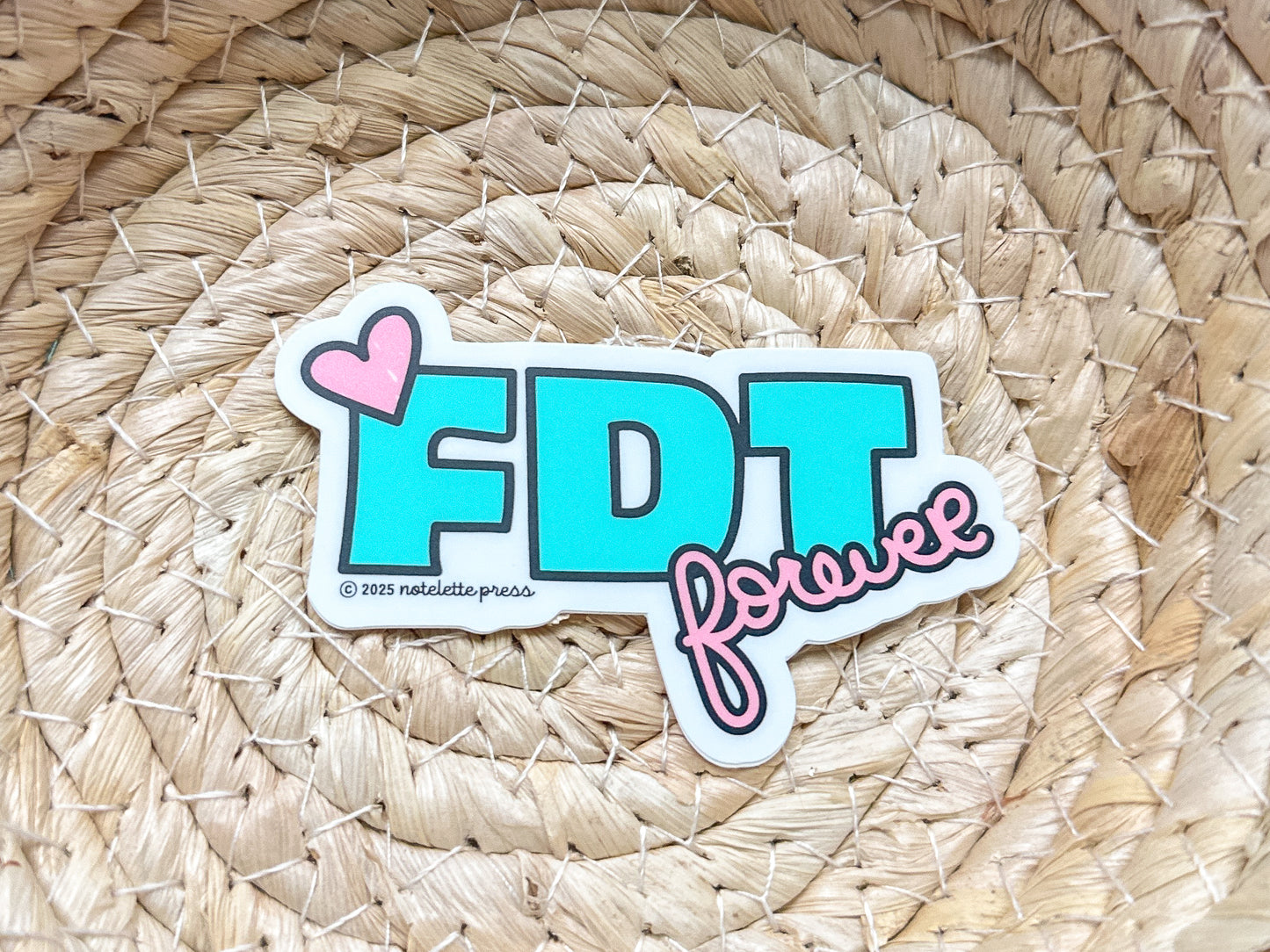 Sticker with 'FDT forever' text on a woven mat
