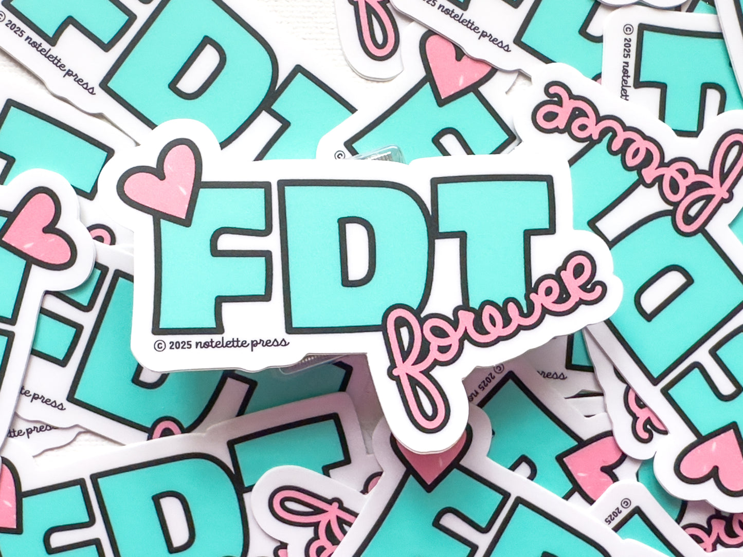 Stack of stickers with 'FDT forever' text and hearts on a white background