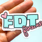Sticker with 'FDT forever' text held in a hand against a light blue background