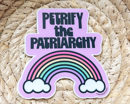 Sticker with rainbow and text 'PETRIFY THE PATRIARCHY' on a woven background